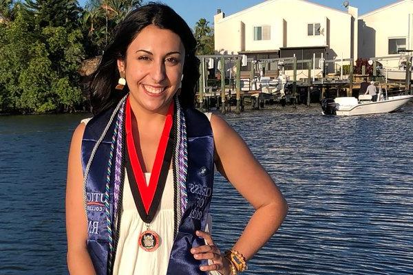 21岁的Kim Slezak在佛罗里达州从加州大学的ABSN项目毕业后站在水边.